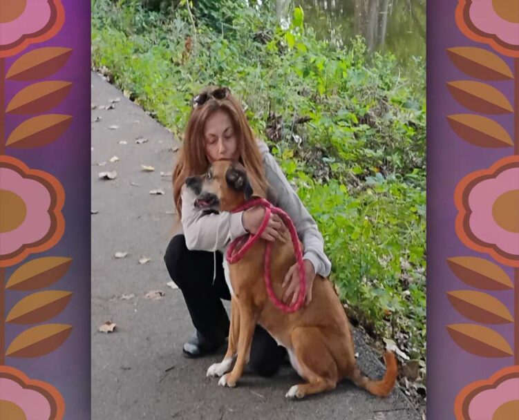 fair skin red headed woman in nature hugging a red dog