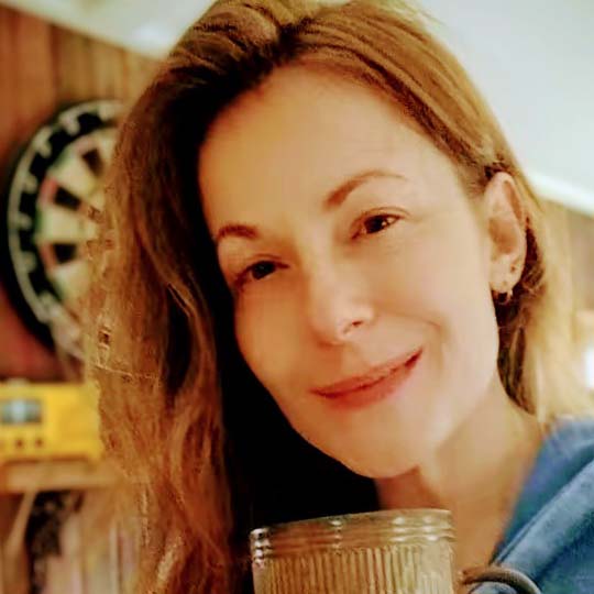Fair skin red headed woman holding a coffee mug smiling.